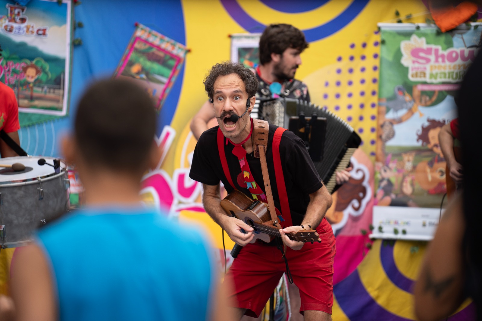 Show infantil do Super Pamp: Edu Pio tocando ukulele no palco